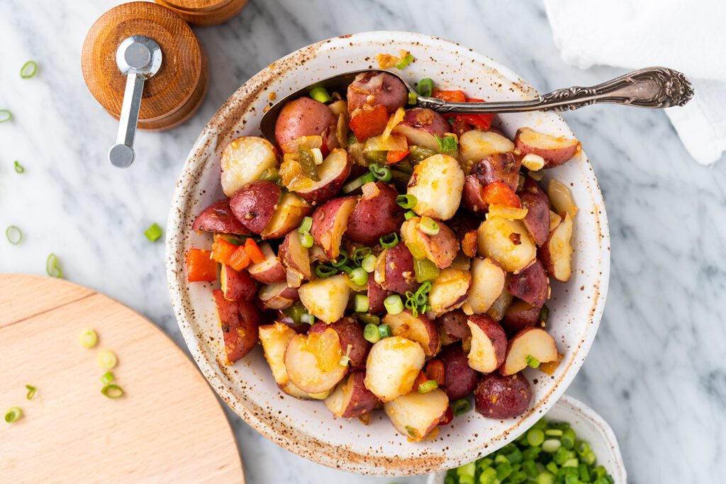 A Bowl of Potato Salad With a Steel Spoon