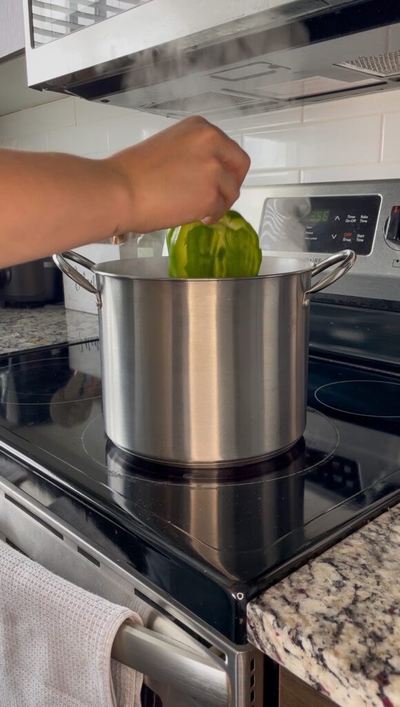 Putting peppers into boiling pot of water on the stove
