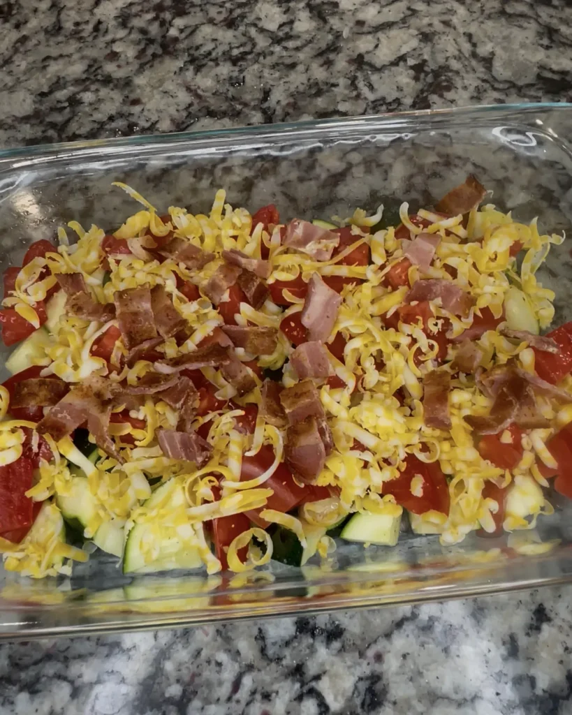 Zucchini, tomatoes, bacon, and cheese layered in a pan
