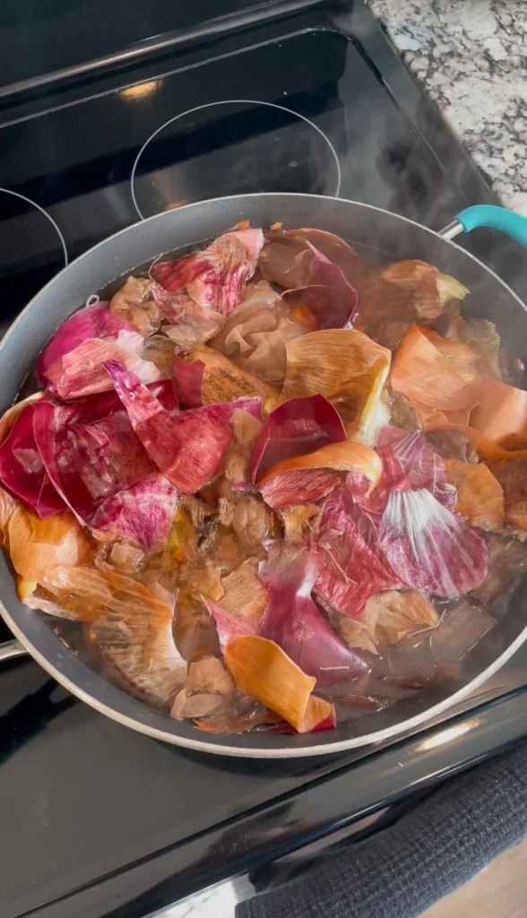 Boiling eggs in nylons with herbs pressed against them to dye Easter eggs naturally with onion skins in a pot of water, vinegar, and onion skins.