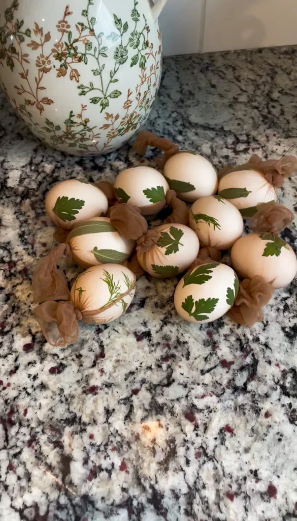 Eggs wrapped in nylon with herbs pressed inside and tied off, sitting on counter.