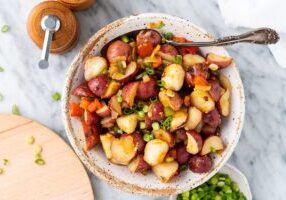 A Bowl of Potato Salad With a Steel Spoon